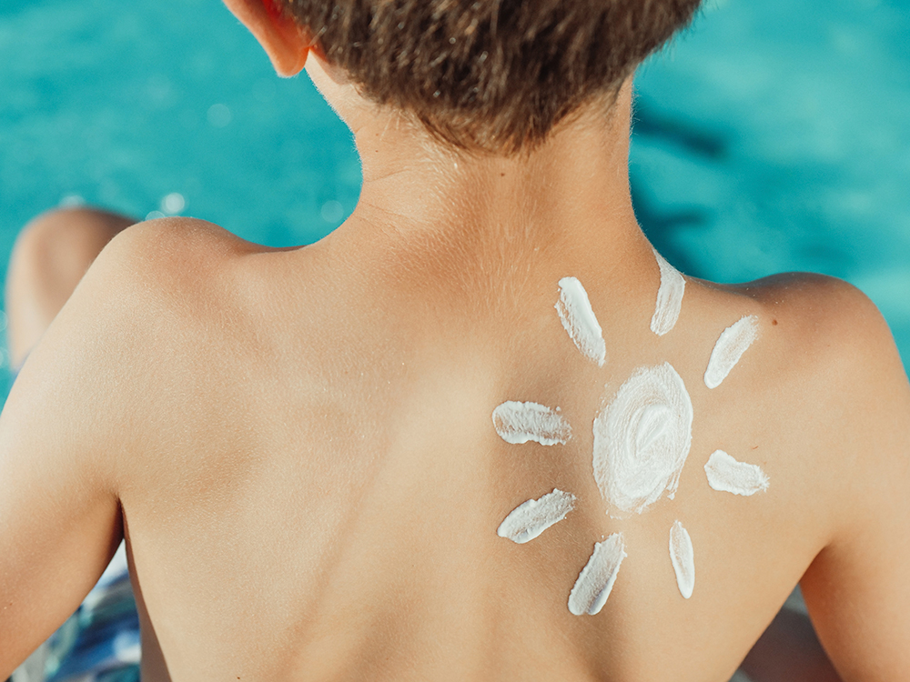 kid's back with a sun drawn with sunscreen
