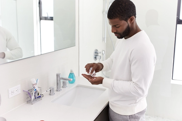 Man in bathroom taking vitamin supplement tablets